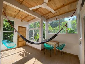a hammock in a room with chairs and a table at Casa Aquila Mazunte in Mazunte
