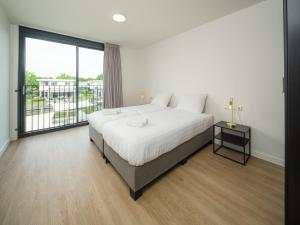 a bedroom with a large bed and a large window at Kubus Nr. 228 | 4 Pers. in Zeewolde +13 photos