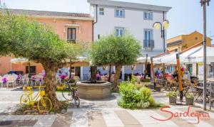 una piazza cittadina con tavoli, sedie e alberi di Casa VALE Holiday Home a Tortolì