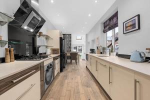 een keuken met witte aanrechtbladen en een kookplaat met oven bij 4 Bedroom House With Cinema Room by City SuperHost in Hale