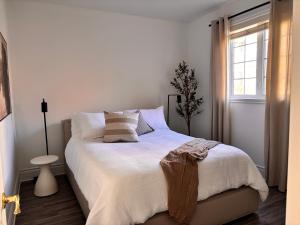 ein Schlafzimmer mit einem Bett mit weißer Bettwäsche und einem Fenster in der Unterkunft MC'S nB in Saint-Sauveur-des-Monts