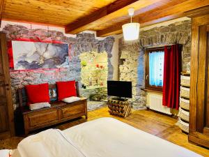 une chambre avec un mur en pierre avec un lit et une télévision dans l'établissement Maison Bovet, à La Salle