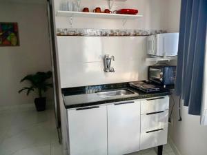 een kleine keuken met een spoelbak en een magnetron bij Tropical Loft in Niterói