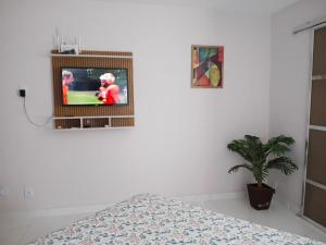 een slaapkamer met een tv aan een witte muur bij Tropical Loft in Niterói