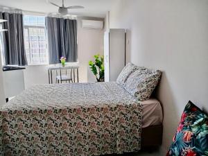 een slaapkamer met een bed, een tafel en een raam bij Tropical Loft in Niterói