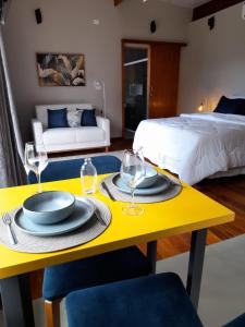 een gele tafel met borden en wijnglazen erop in een slaapkamer bij Chalé Topázio Gonçalves in Gonçalves