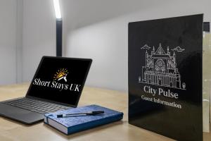 Ein Buch und ein Laptop lagen auf einem Tisch, daneben ein Reisepass. in der Unterkunft City Pulse Apartment- Short Stays UK in Exeter