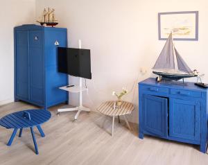 ein Wohnzimmer mit blauen Möbeln und einem TV in der Unterkunft La goélette - Les Gîtes de la Côte d'Amour in Le Croisic