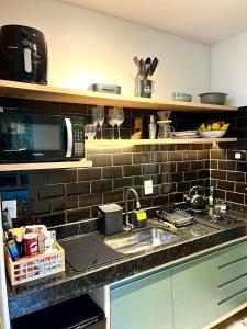 un bancone da cucina con lavello e microonde di Villa Manah a Itaúnas