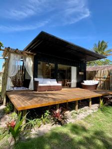 una terrazza in legno con un letto e una casa di Villa Manah a Itaúnas Altre 13 foto