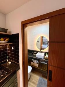 a bathroom with a toilet and a sink and a mirror at Villa Manah in Itaúnas