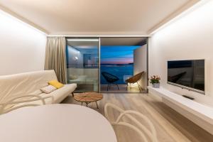 Una sala de estar con un sofá blanco y un televisor. en Sud Ibiza Suites, en Ibiza