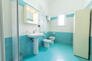 ein blau gefliestes Badezimmer mit Waschbecken und Toilette in der Unterkunft CORAL BAY Apartment in Porto Cesareo + 12 Fotos