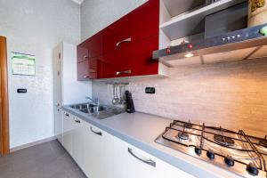eine Küche mit roten Schränken und einem Herd in der Unterkunft CORAL BAY Apartment in Porto Cesareo