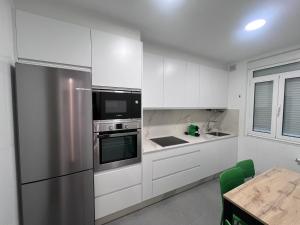a kitchen with white cabinets and a stainless steel refrigerator at Céntrico Apartamento con parking in A Coruña +10 photos