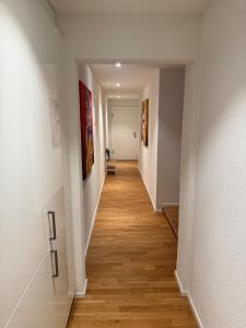 a hallway with white walls and wood floors and paintings at Pop-up design studio Workplace central location in St. Gallen