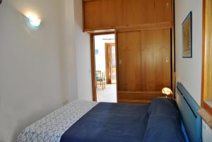 a bedroom with a blue bed and a wooden door at Casa Simon tra mare e natura in Sperlonga