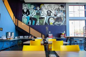a restaurant with yellow chairs and a mural on the wall at Hotel Modular Express Calama in Calama