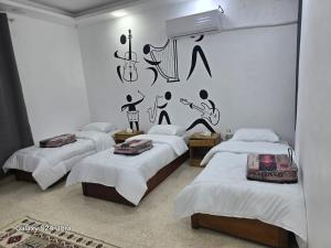 een kamer met drie bedden en muziek aan de muur bij Lukanda Apartment Feel at Home in Amman