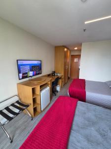 a room with a bed and a desk with a television at Flat 1015 - Comfort Hotel Taguatinga in Brasilia
