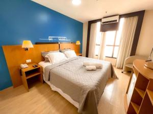 a bedroom with a large bed with a blue wall at Flat 1015 - Hotel Comfort Taguatinga in Brasília