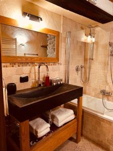 La salle de bains est pourvue d'un lavabo noir et d'une baignoire. dans l'établissement Maison Bovet, à La Salle