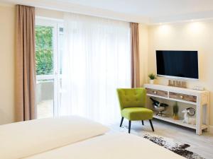 una camera da letto con televisore e sedia verde di Donau Lodge Boardinghouse a Straubing