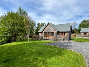 una casa con un patio verde y una casa en Kestrel Lodge 2 with Hot Tub, en Newton Stewart