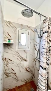ein Bad mit Marmorwänden und einer Dusche in der Unterkunft Elina's Rooms in Poros