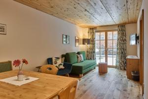 a living room with a table and a green couch at Appartement Omesberg 1 in Lech am Arlberg