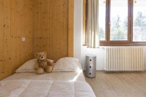 um urso de peluche sentado numa cama num quarto em Résidence & Spa La Grande Cordée - Combloux em Combloux