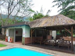 een paviljoen met een tafel en banken naast een zwembad bij 115 Eden wilds in Port Edward