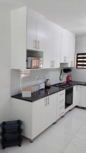 een keuken met witte kasten en een zwart aanrechtblad bij 115 Eden wilds in Port Edward