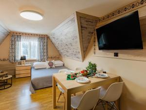 een woonkamer met een tafel en een tv aan de muur bij WERONIKA Murzasichle in Murzasichle +147 foto's