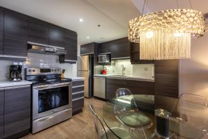 eine Küche mit einem Glastisch und einem Kronleuchter in der Unterkunft Les Immeubles Charlevoix - Le 1166 in Québec