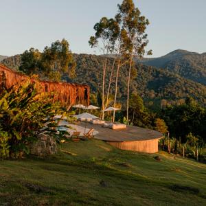 a building with chairs and umbrellas on top of a field at Mōmento Itamambuca in Ubatuba
