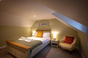 een kleine slaapkamer met een bed en een stoel bij Dunvegan Castle Rose Valley Cottage in Dunvegan +7 foto's