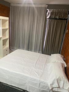 une chambre avec un lit blanc avec une fenêtre dans l'établissement Libertad, à Clorinda