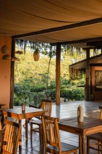 a dining room with wooden tables and chairs and a large window at Mōmento Itamambuca in Ubatuba