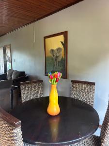un tavolo da pranzo con un vaso giallo con dei fiori sopra di Protea Guesthouse a Phalaborwa