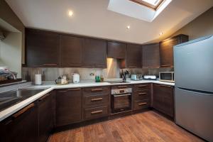 een keuken met houten kasten en een roestvrijstalen koelkast bij Dunvegan Castle Rose Valley Cottage in Dunvegan