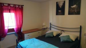een slaapkamer met een bed en een raam met rode gordijnen bij Casa Vacanza Bettega in Pianosinatico