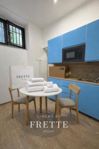 una cucina con mobili blu e un tavolo e sedie bianchi di Cìvitas Suite ApartHotel a Catania