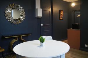 een eetkamer met een witte tafel en een spiegel bij Résidence Saint Pôl in Nogent-le-Rotrou