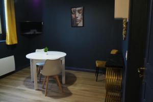 een witte tafel en stoelen in een kamer met een blauwe muur bij Résidence Saint Pôl in Nogent-le-Rotrou