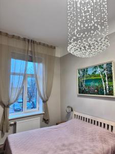 ein Schlafzimmer mit einem großen Bett und einem Kronleuchter in der Unterkunft Saulgrieži 7 in Ventspils