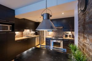 a kitchen with black cabinets and a large pendant light at Les Immeubles Charlevoix - Le 1168 in Quebec City