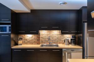 a kitchen with black cabinets and a sink at Les Immeubles Charlevoix - Le 1168 in Quebec City