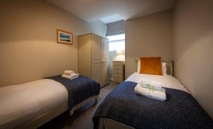 een kleine slaapkamer met twee bedden en een raam bij Dunvegan Castle Laundry Cottage in Dunvegan