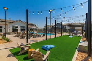 een patio met een gazon met stoelen en een zwembad bij Landing Apartments - Longmont in Firestone